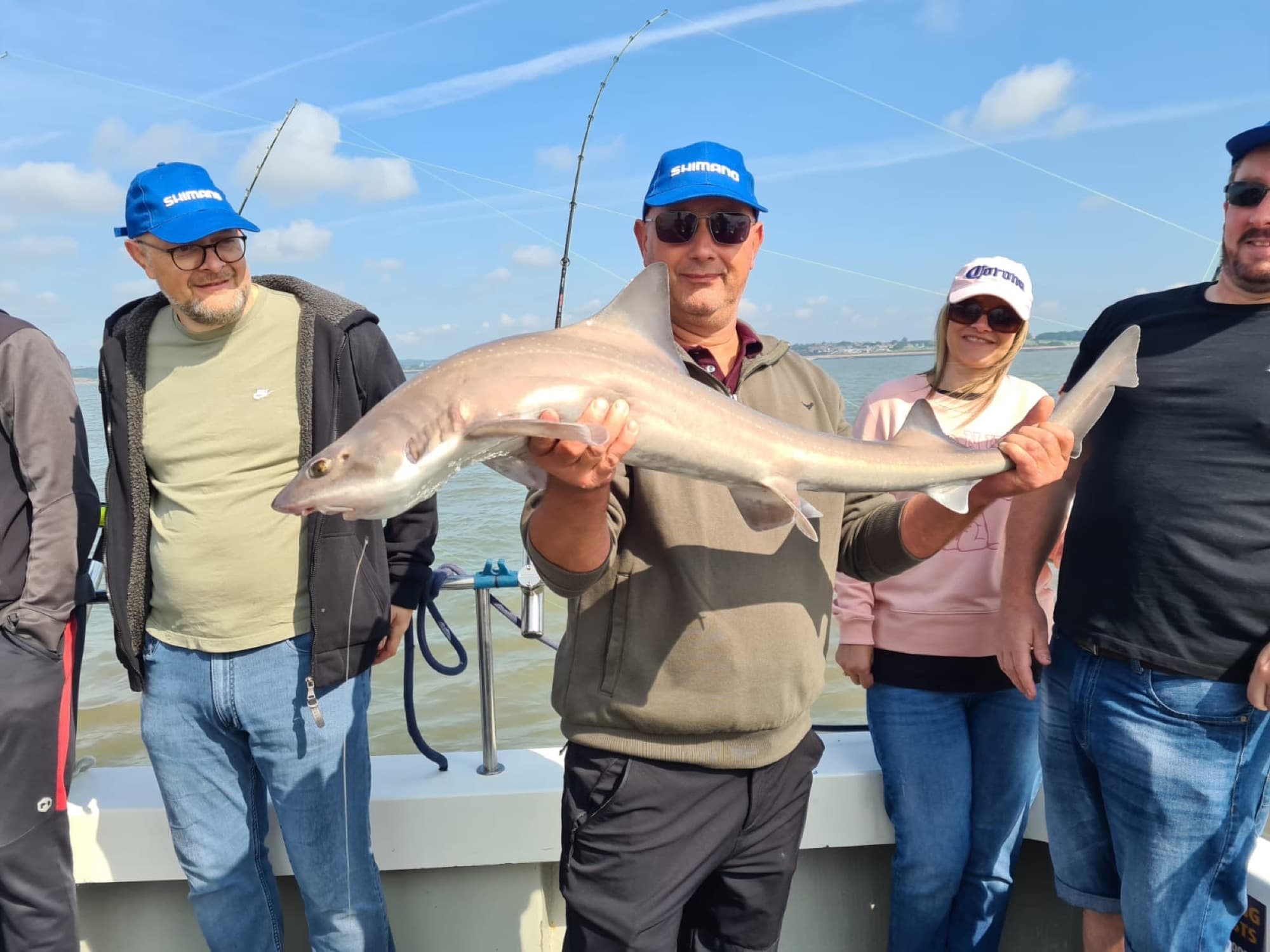A group of friends posing with a smooth-hound on the back deck