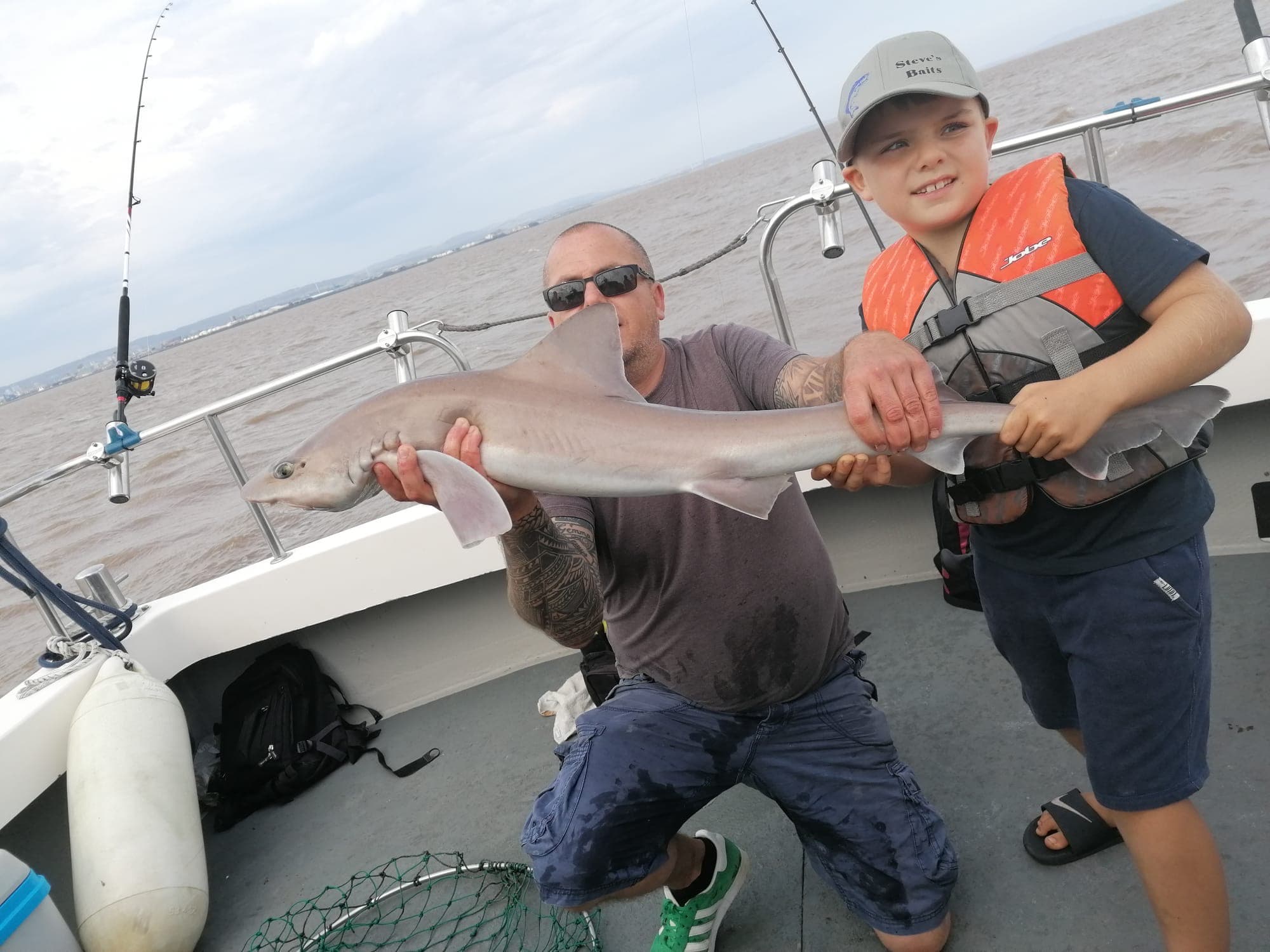 Father and son together holding a smooth-hound