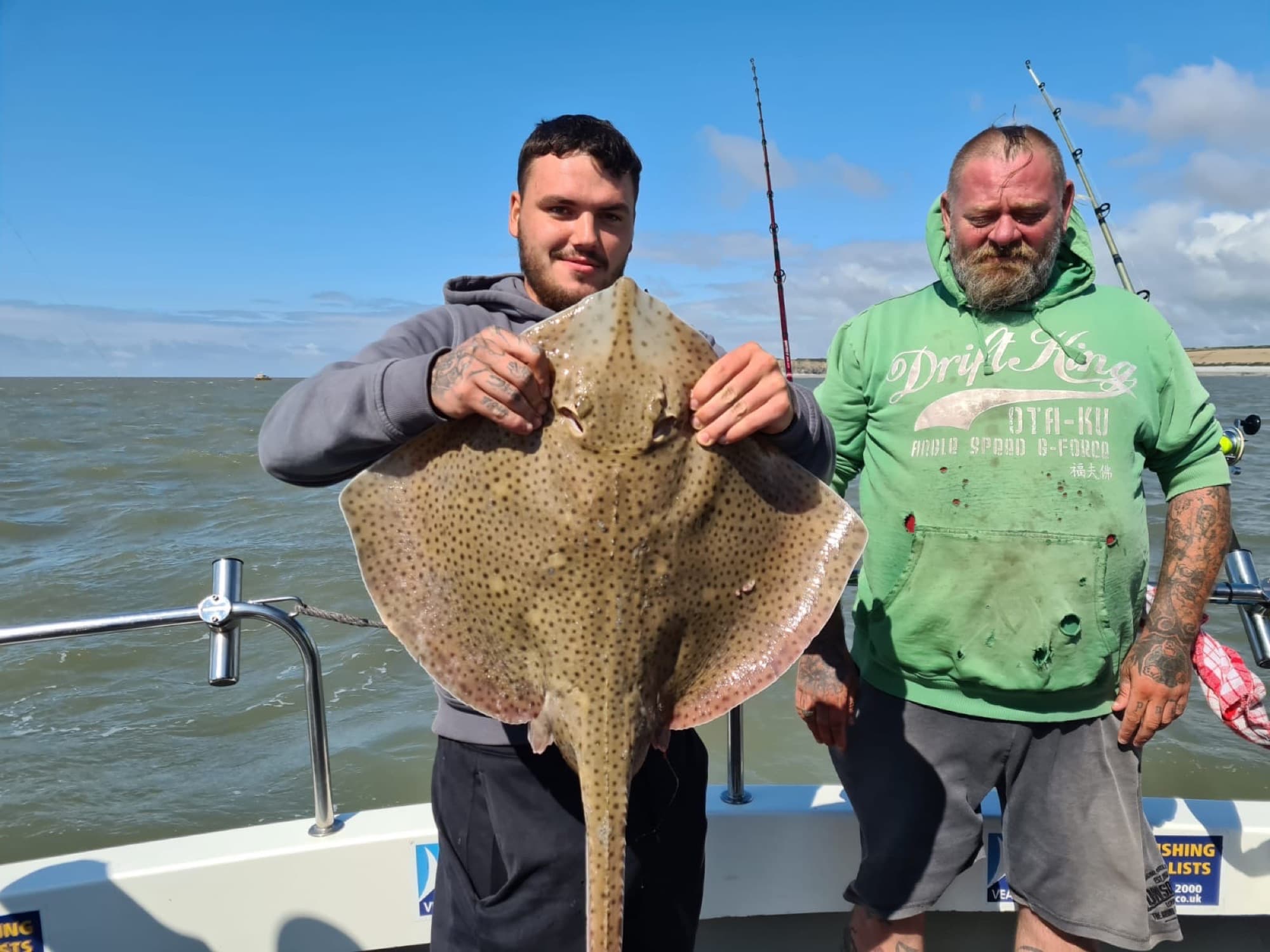 Two anglers proudly displaying a big blonde ray